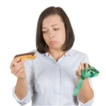 Młoda kobieta wybierająca między czekoladowym eklerem a zdrowiem