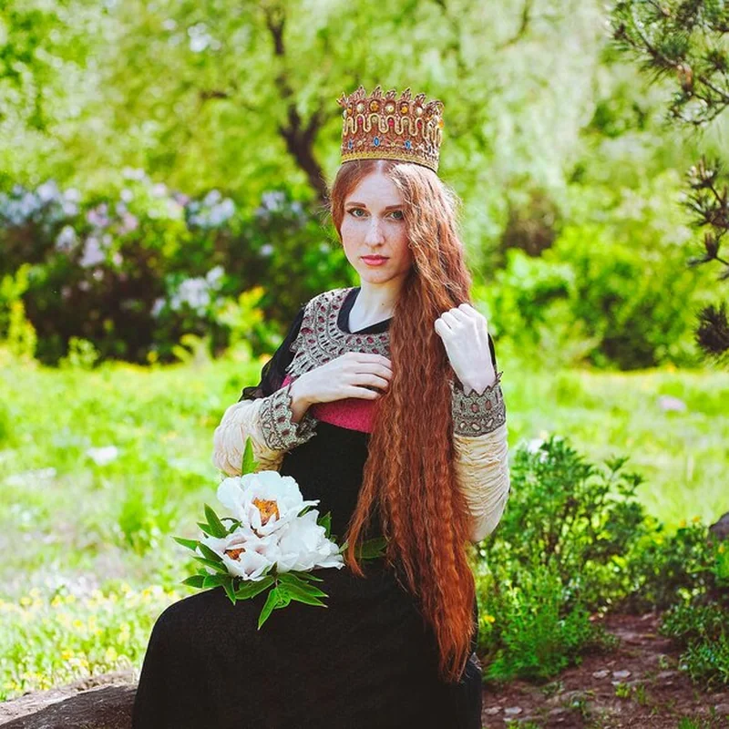 Młoda kobieta z rudymi włosami w zabytkowej sukience w ogrodzie