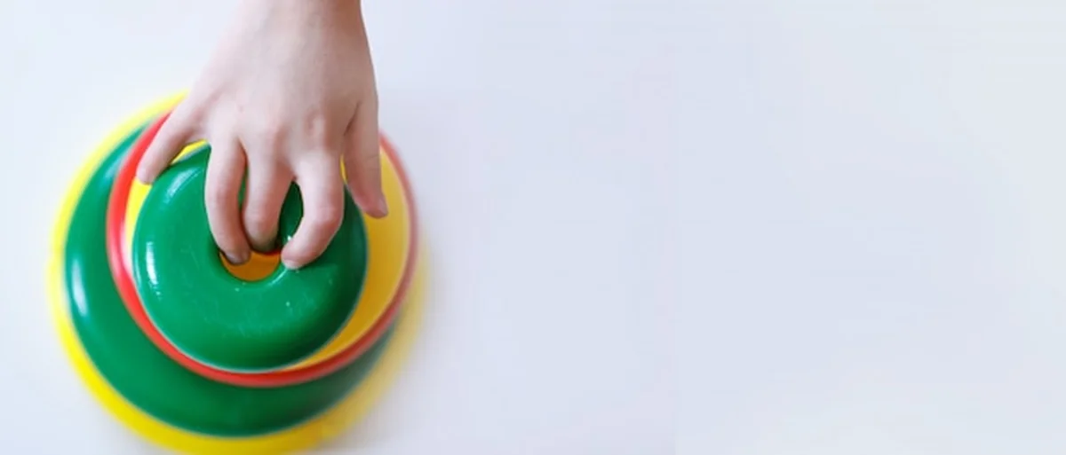 Dziecko zbiera piramidę. Szczegóły zabawki w rękach