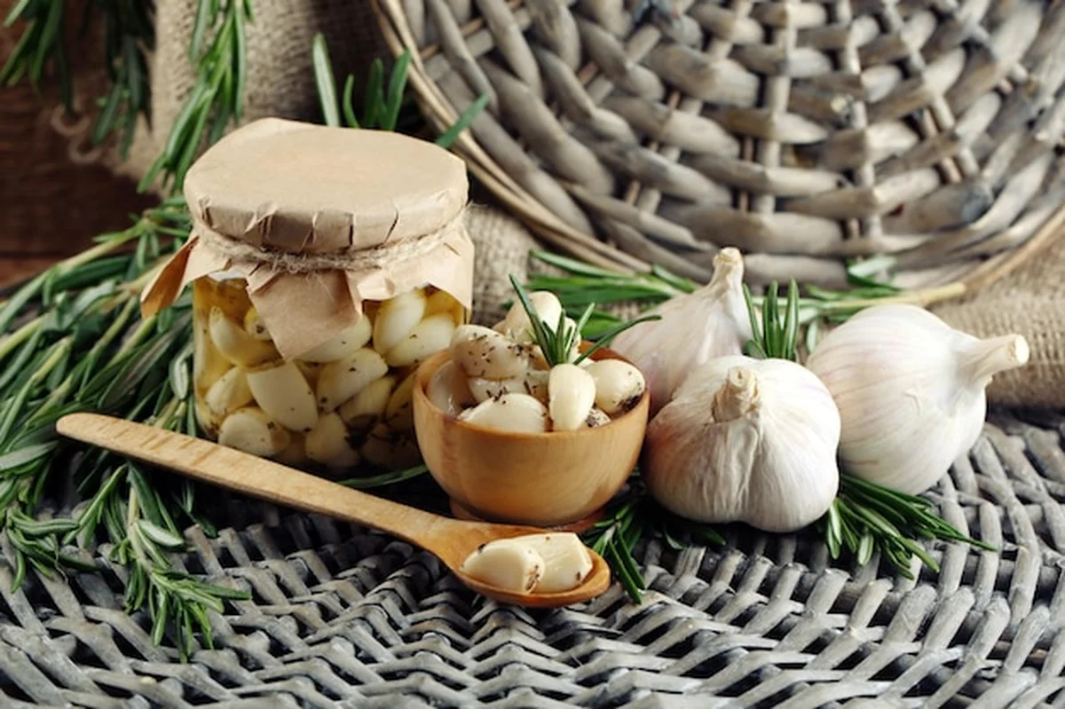 Konserwowy czosnek w słoiku z rozmarynem na podłodze