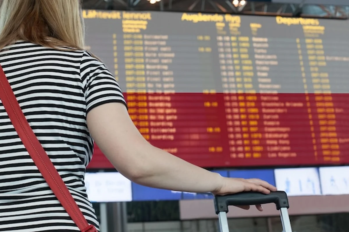 Kobieta patrzy na tablicę wyników na lotnisku