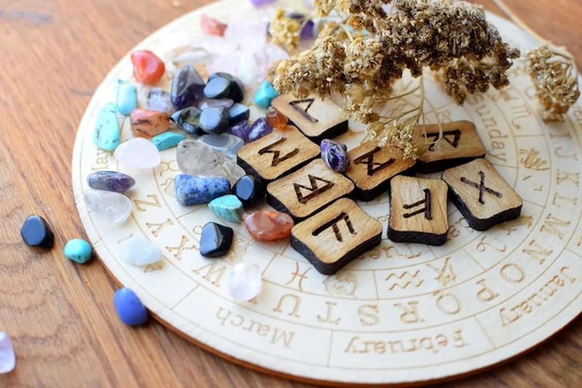 Skandynawskie runy z ametystu i kwarcu różanego na tablicy z symbolami zodiaku