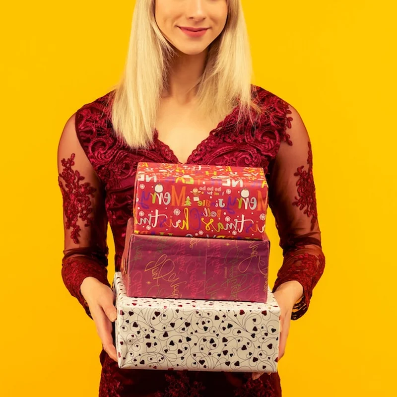 Kobieta w sylwestrowym kapeluszu trzymająca prezenty