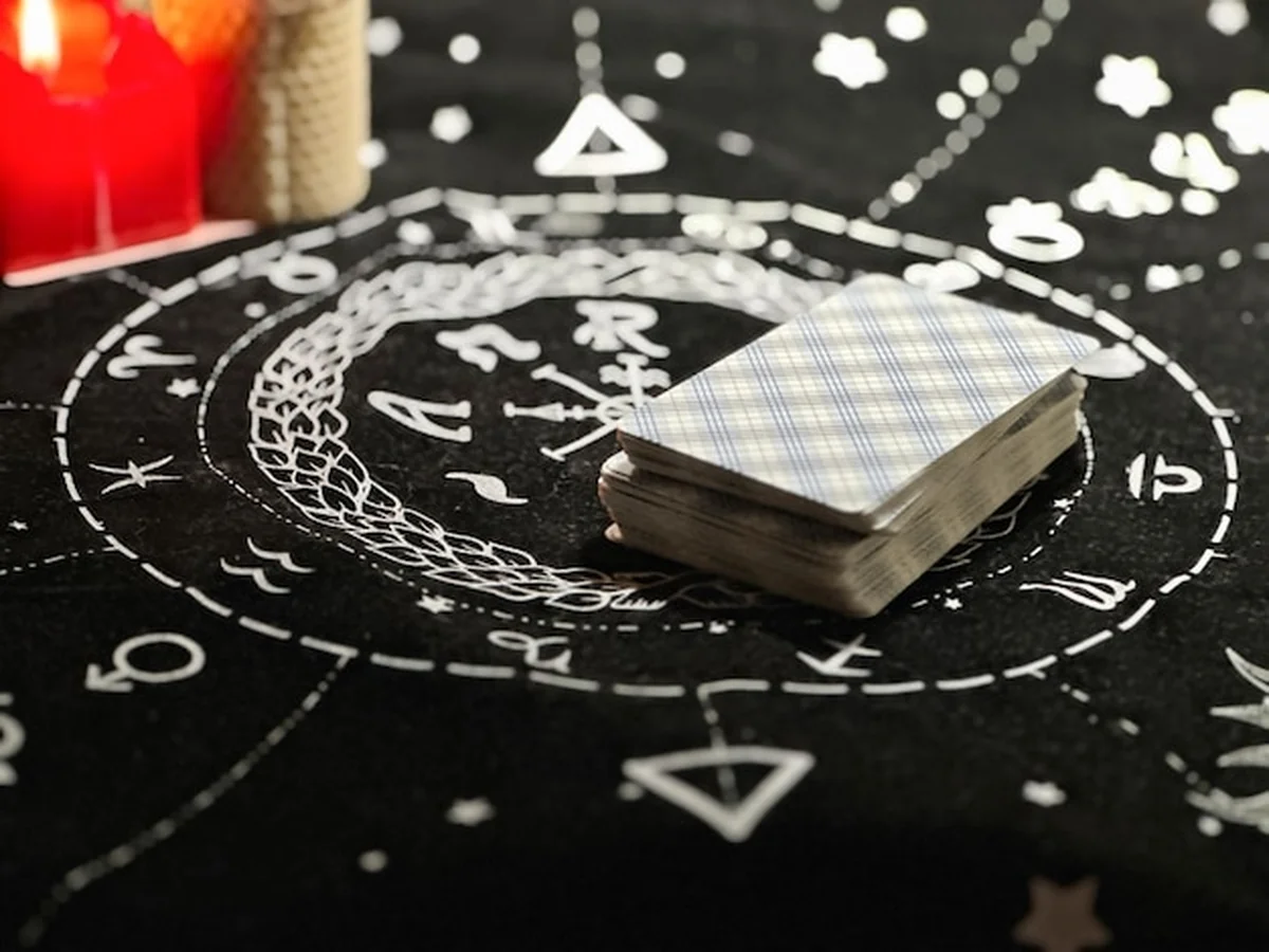 Karty Tarota na stole obok palących się świec